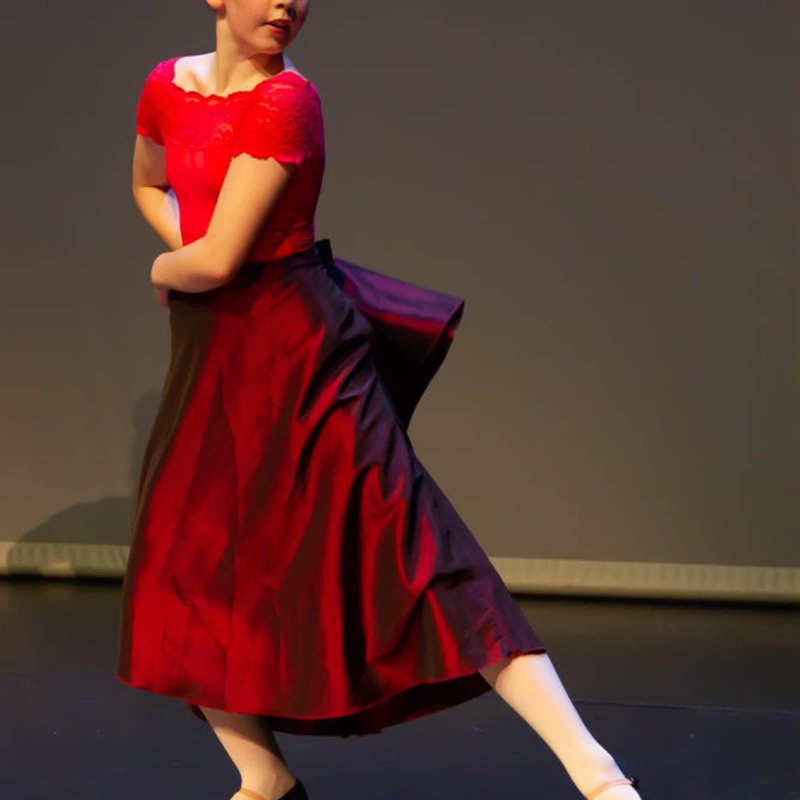 Solo dancer in a red lace top and burgundy character skirt