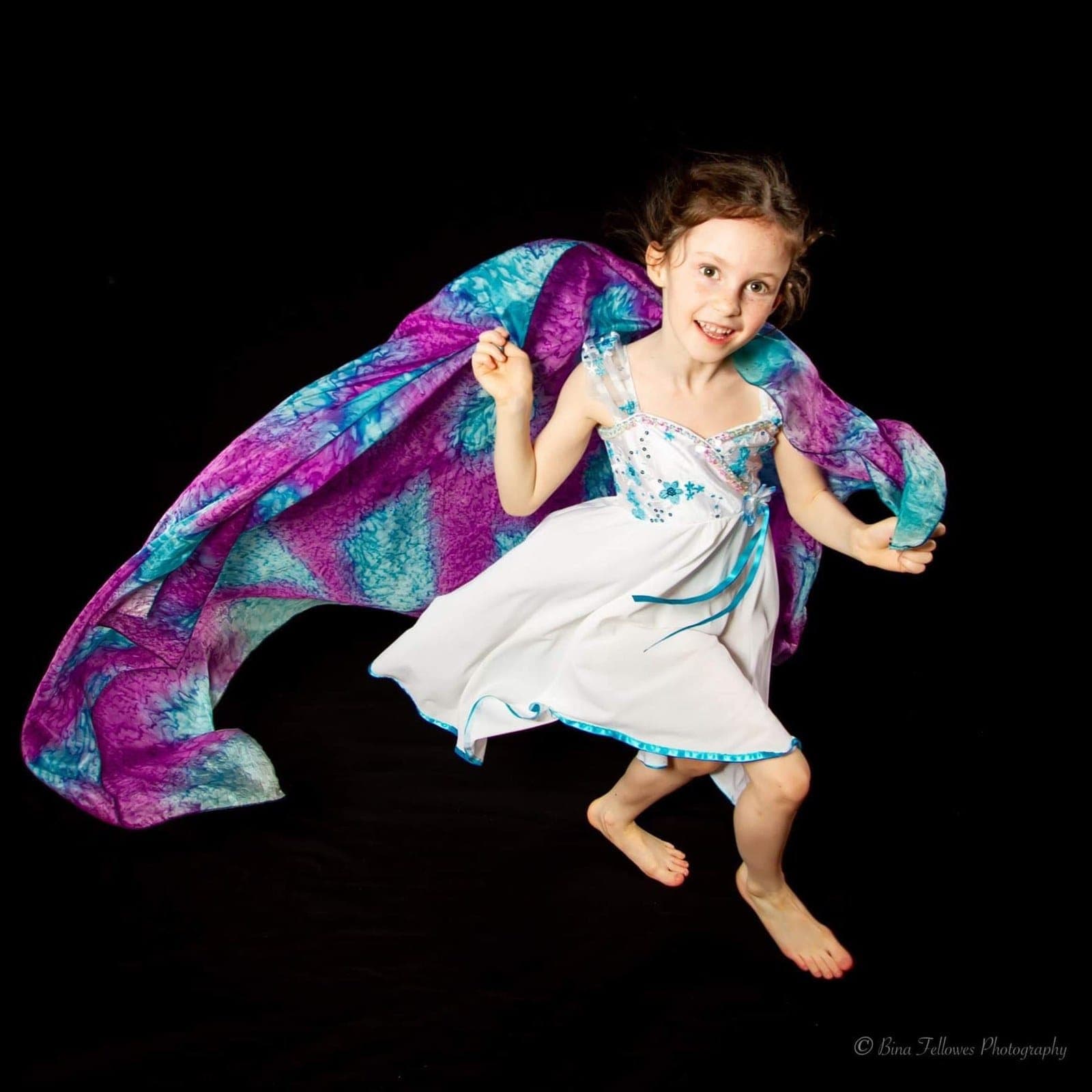 Young dancer leaping with a colourful silk scarf