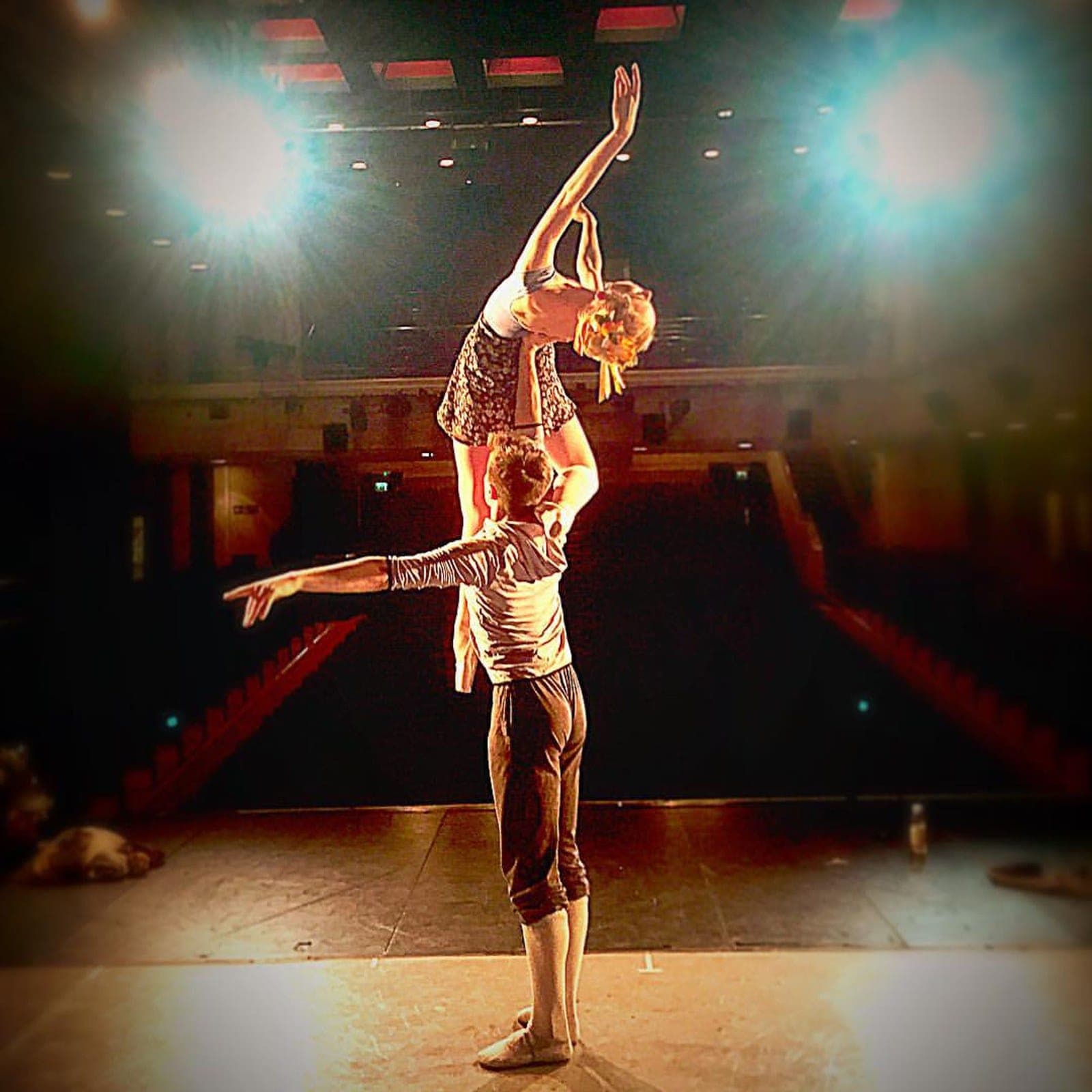 Partnered lift on stage with theatre seats in the background