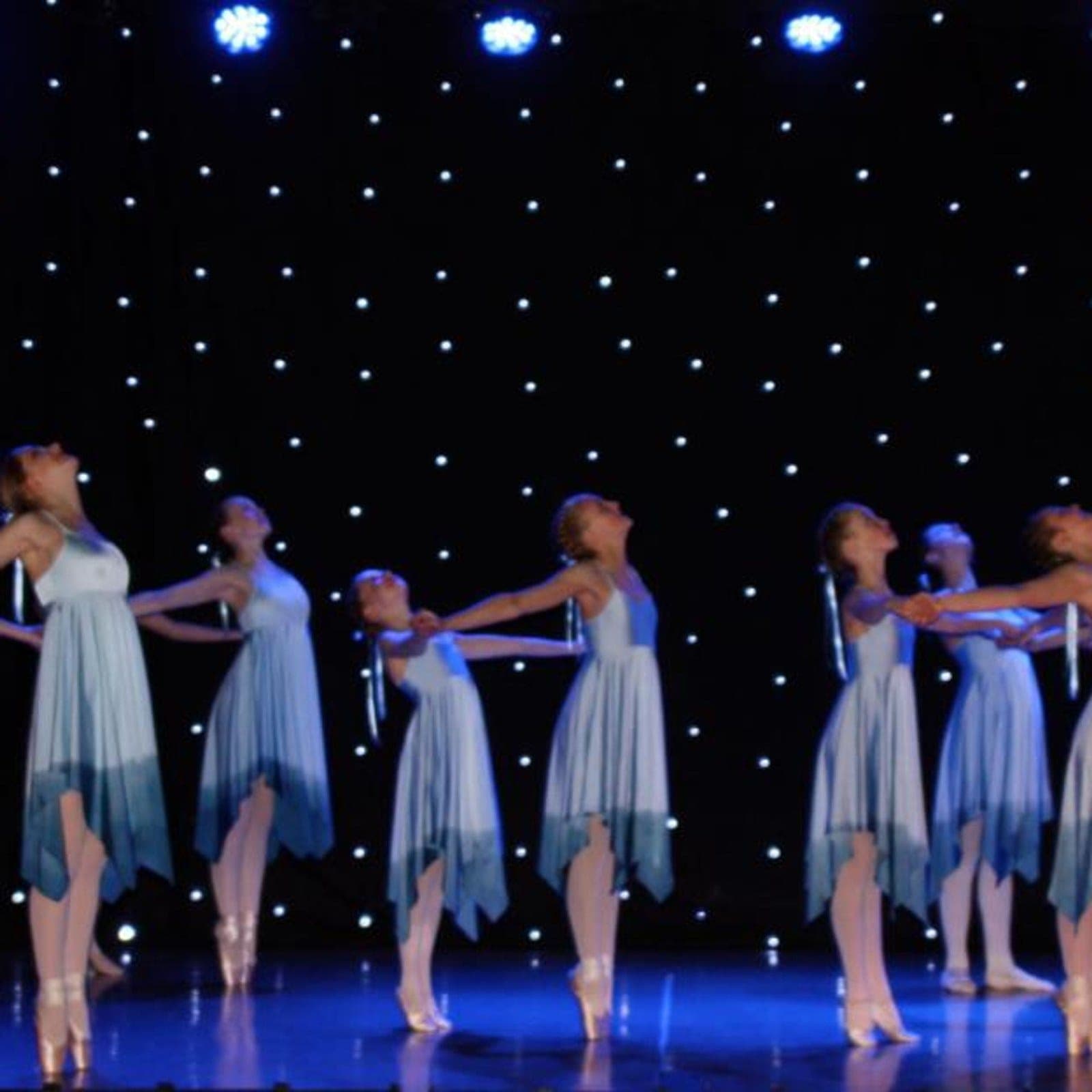 Dancers en pointe in blue ombré dresses under star cloth lighting